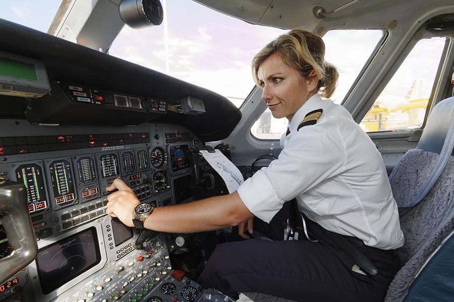 Female pilot adjusting aircraft controls in cockpit during professional flight operations.