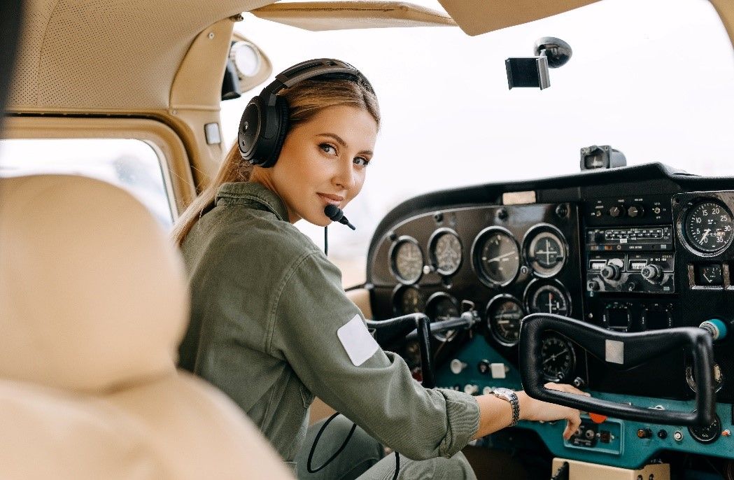 Student pilot in headset operating cockpit controls during flight training.