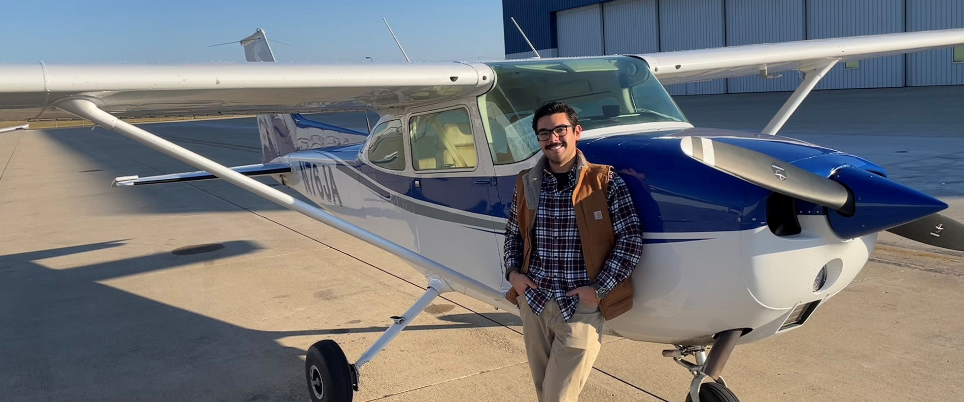 Student pilot Ben Graca standing beside single-engine training aircraft on airport ramp.