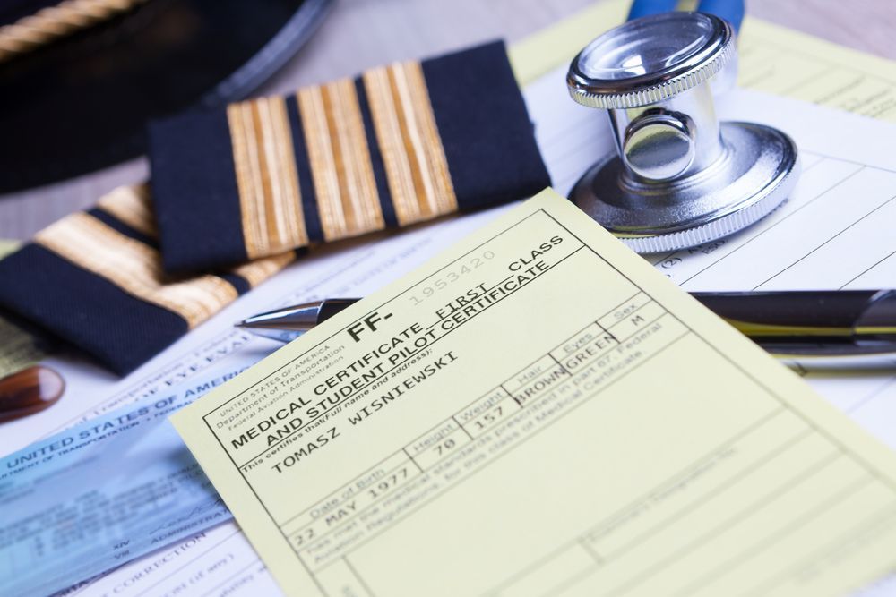 A closeup of an airplane pilot's first class medical certificate and student pilot certificate.
