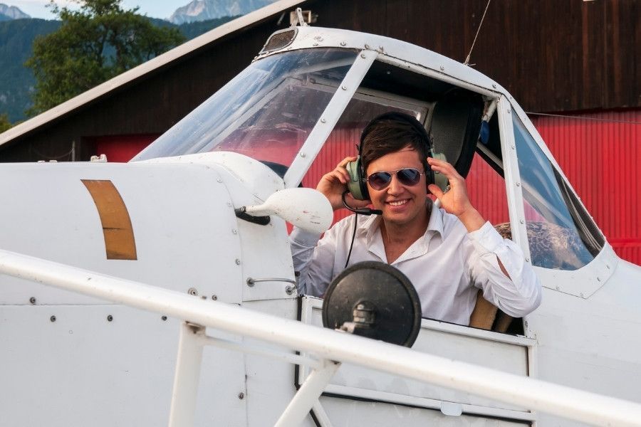 Smiling student pilot wearing headset seated in small training aircraft cockpit.