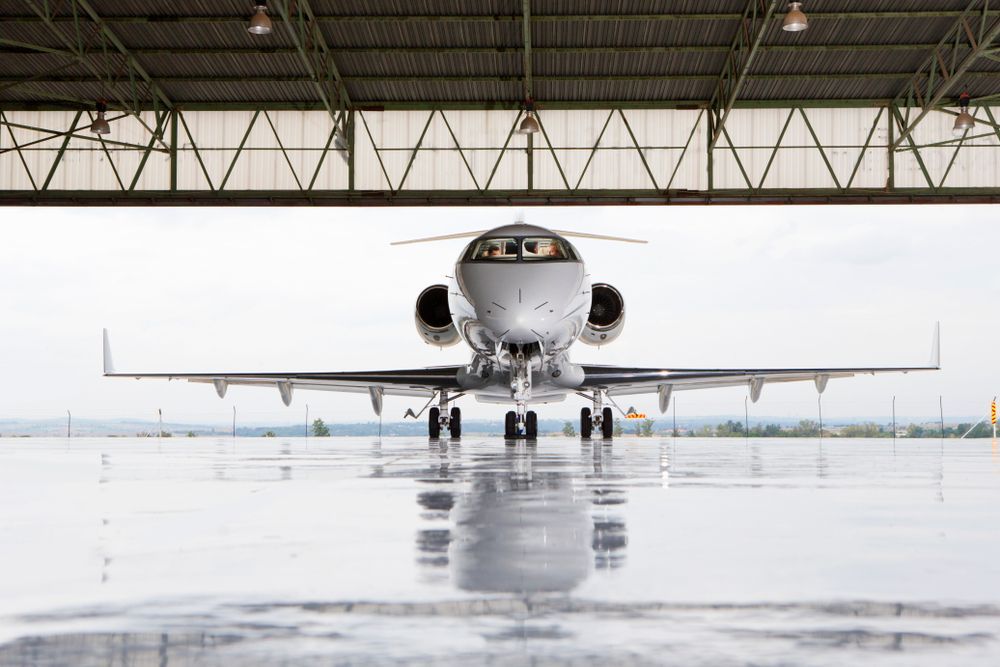 Business jet parked in a hangar with its nose facing out toward the runway.