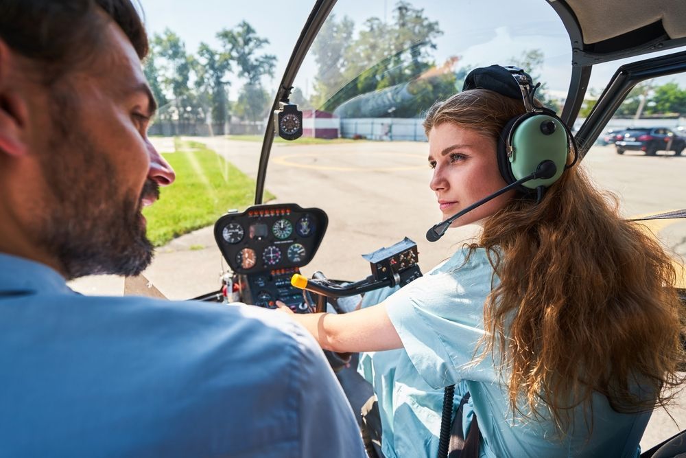A man is teaching a woman how to fly a helicopter.