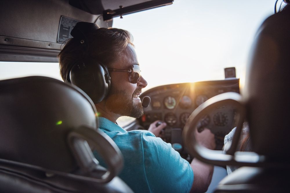 A man wearing headphones is sitting in the cockpit of an airplane.