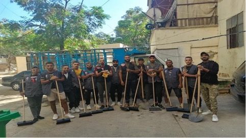 A group of men standing next to each other holding brooms and shovels