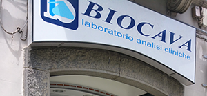 Insegna del laboratorio di analisi cliniche Biocava sopra un ingresso ad arco.