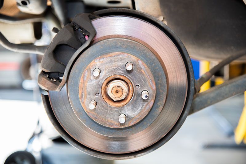 Car brake rotor and caliper close-up with wheel removed