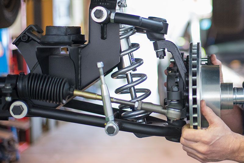 Car suspension assembly with coil spring and brake rotor being held by a person’s hands