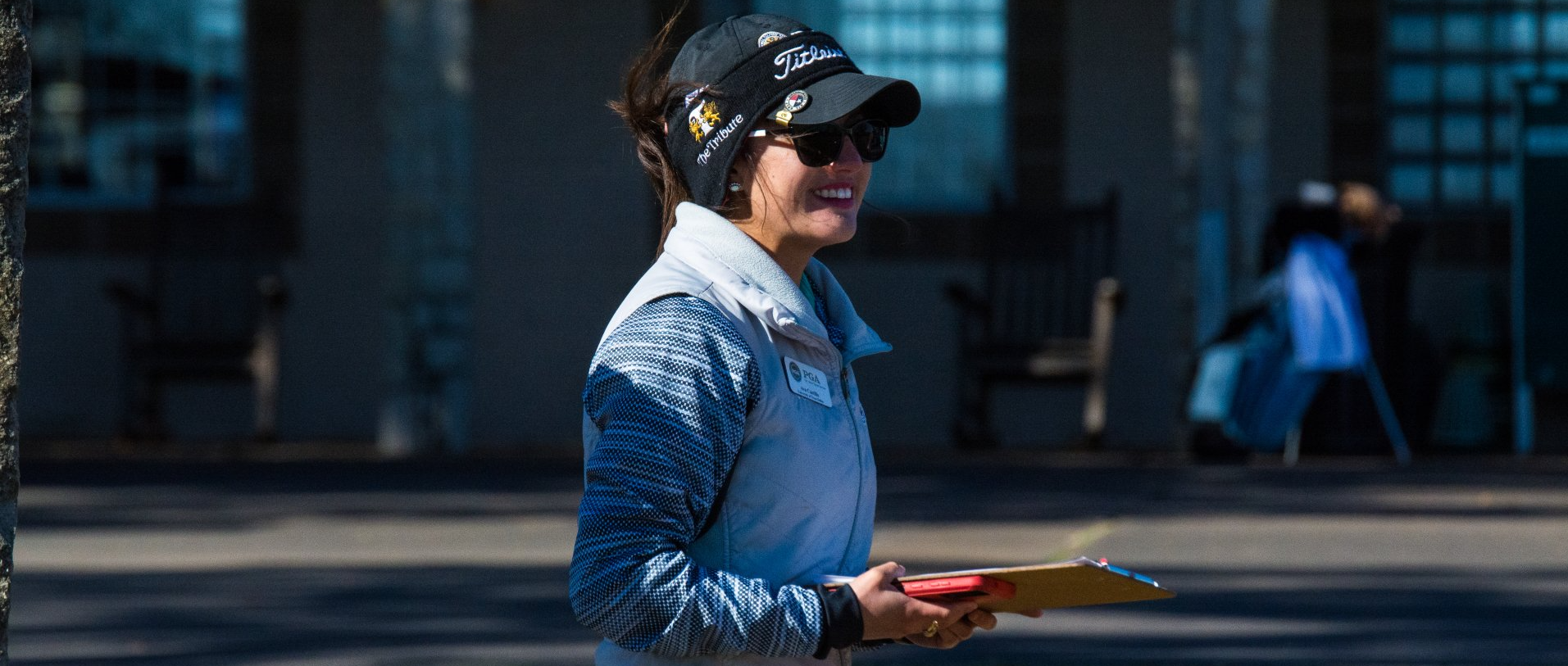 Person in blue shirt and cap holding a tray outdoors in front of a building