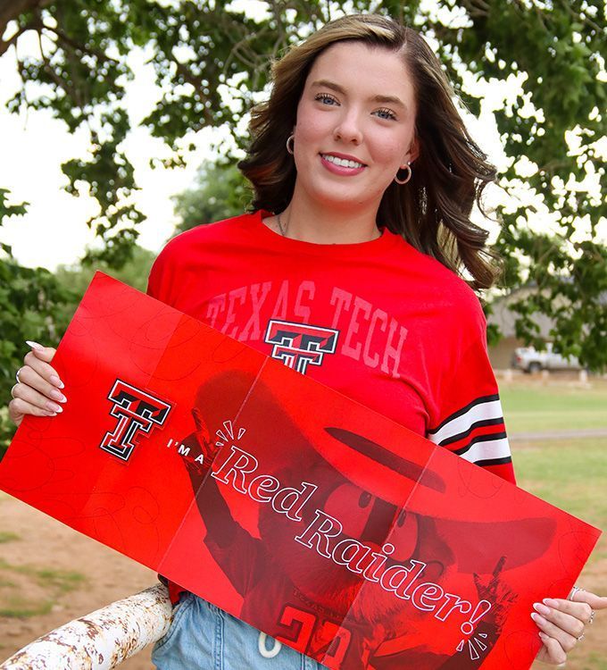 Woman in a red Texas Tech shirt holding a red Texas Tech sign outdoors