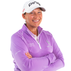 Smiling person in a white cap and purple jacket with arms crossed against a white background