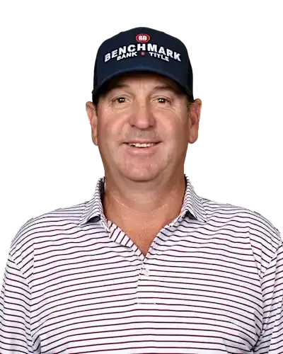 Smiling person in a navy Benchmark cap and striped polo shirt against a white background