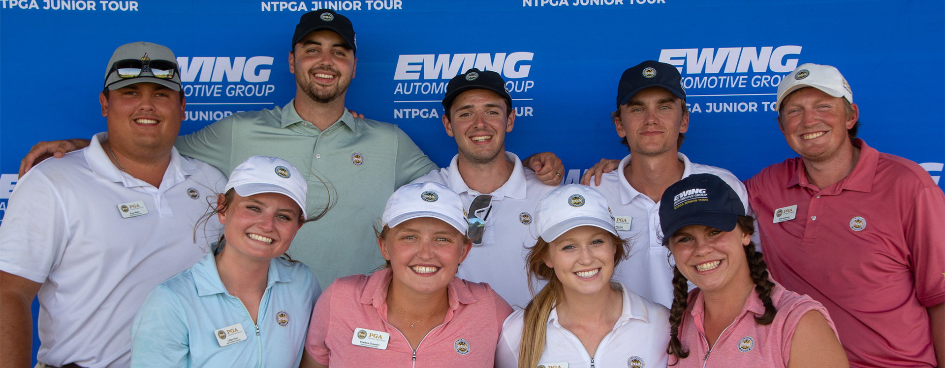 Eight people posing in front of a blue EVWING backdrop at a golf event, smiling in team shirts and caps