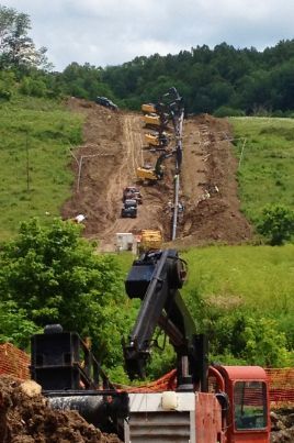 A group of construction vehicles are working on a hillside