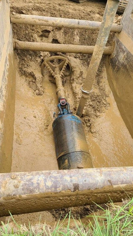 A large yellow excavator is digging a hole in the dirt.