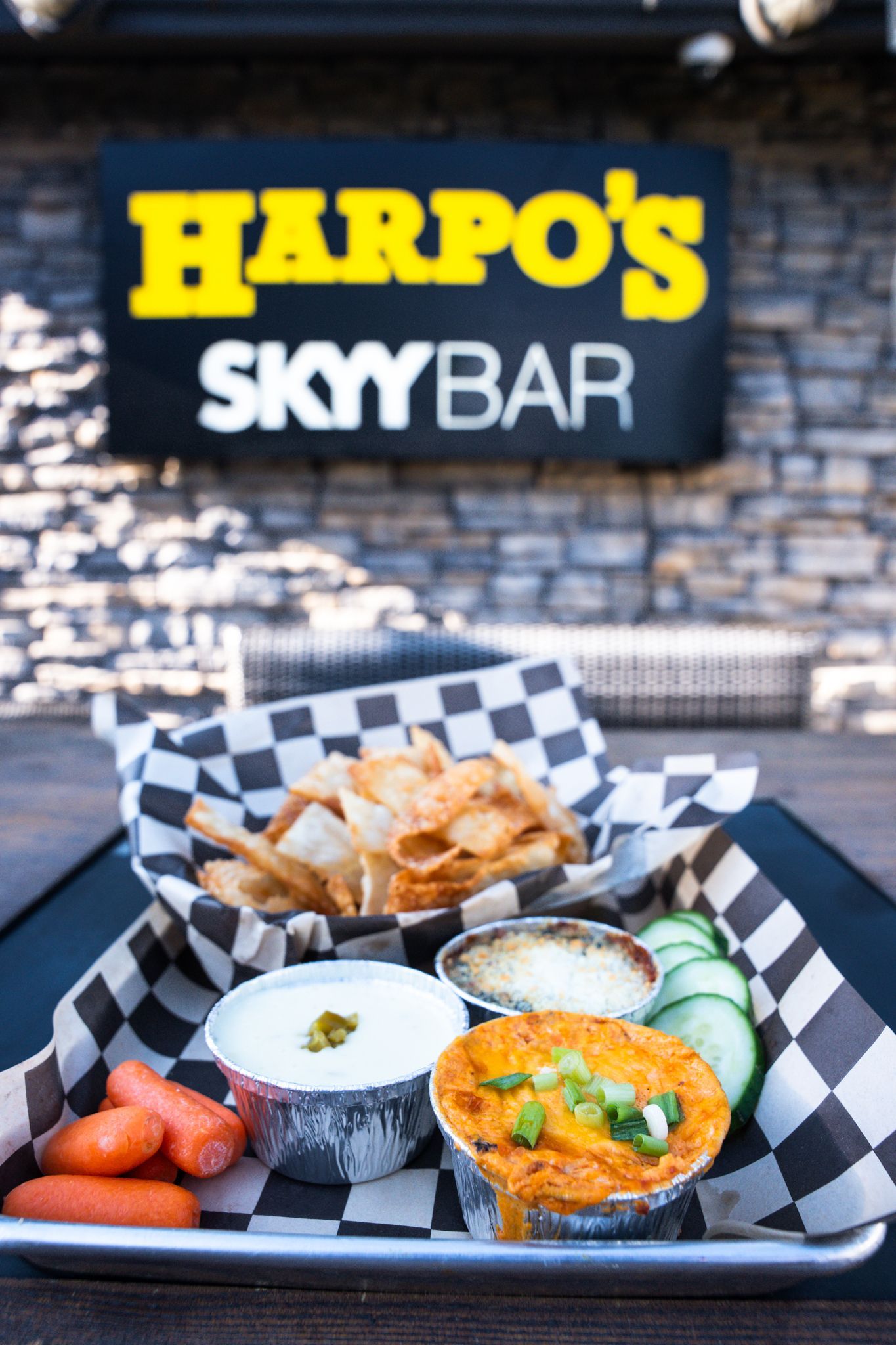 Brunch tray with eggs, potatoes, tomatoes, and dip at Harpo’s Sky Bar, with sign in background