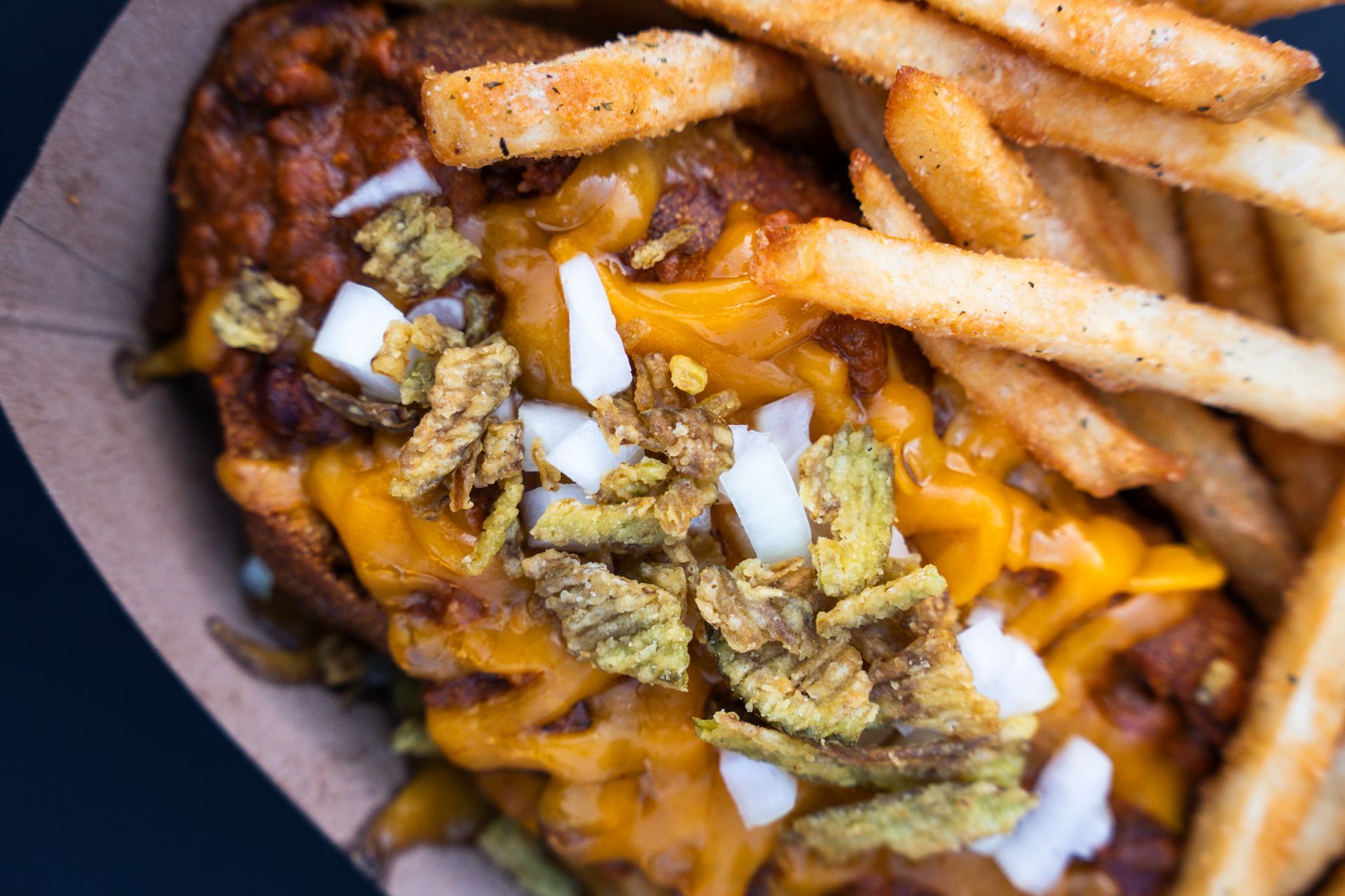 Loaded fries topped with melted cheese, bacon, and chopped onions in a bowl