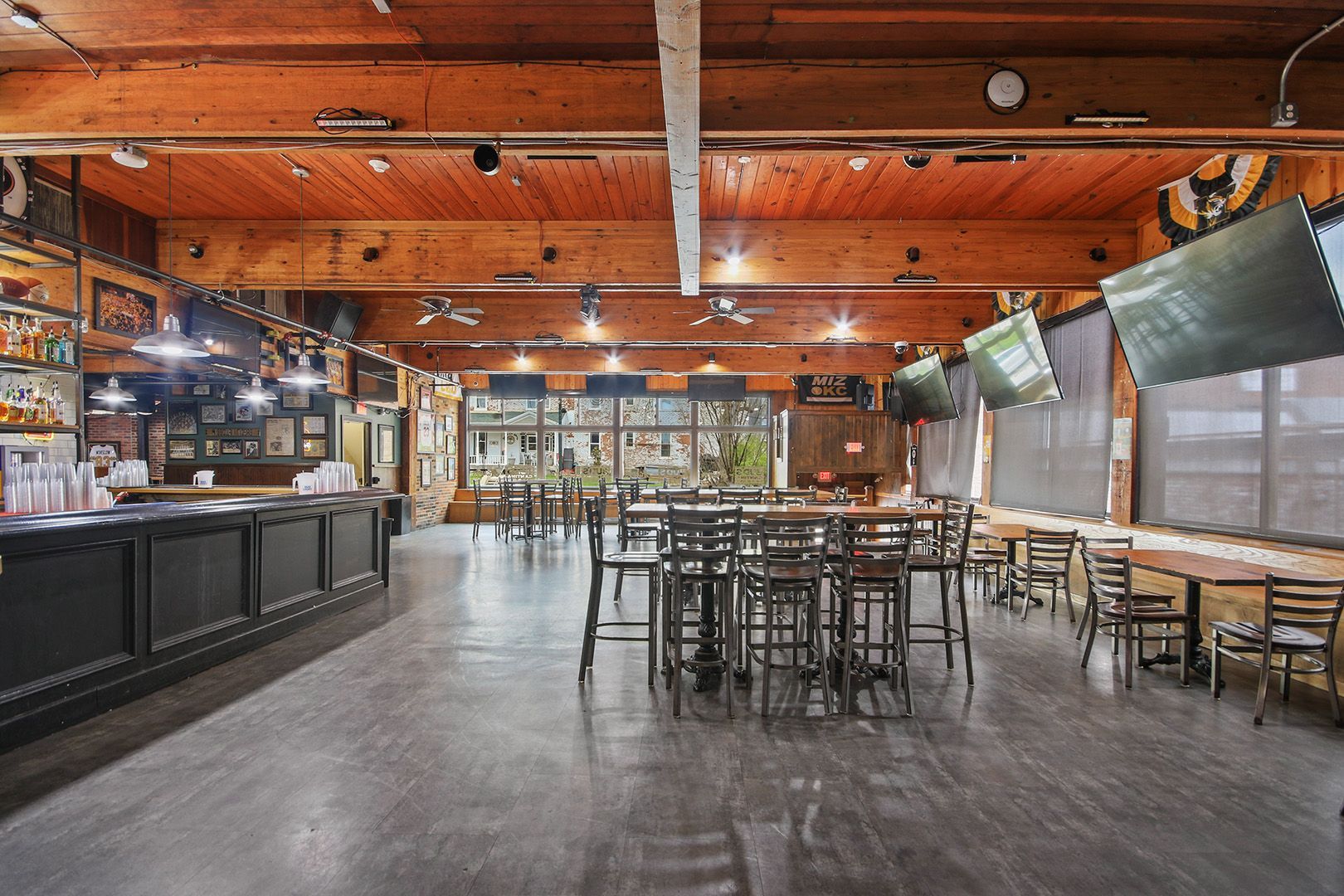 A large empty restaurant with tables and chairs and a bar.
