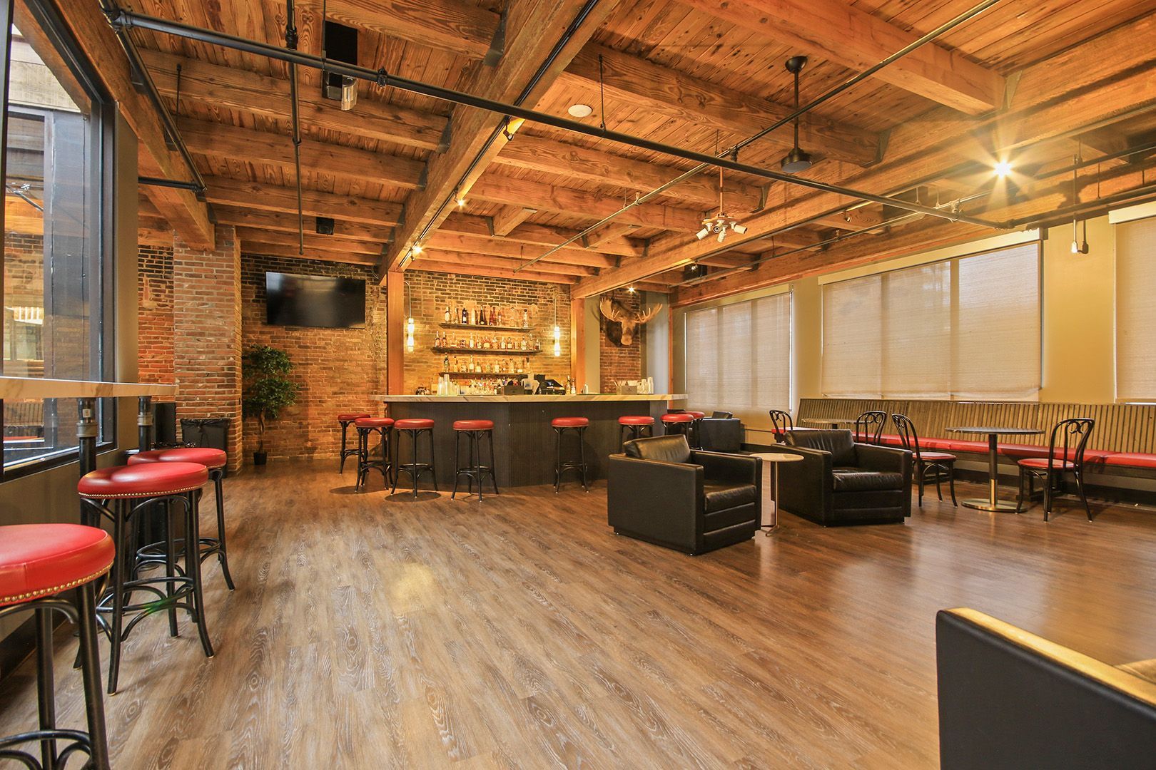 A large room with a bar , chairs , tables and stools.