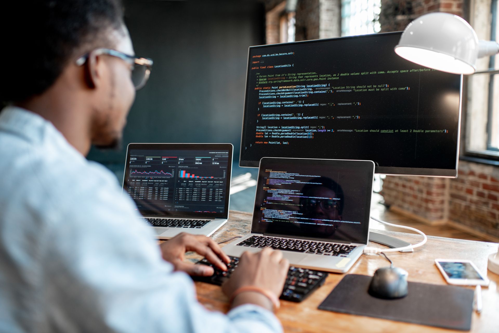 A person coding on multiple screens in an office setting.