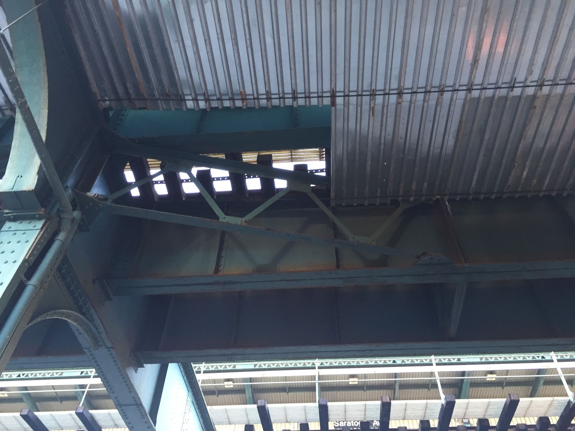 View from below of a metal bridge structure with a missing section of roofing.