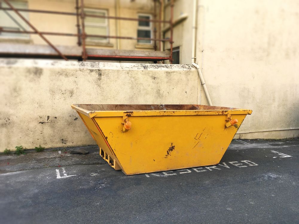 Yellow construction dumpster beside a concrete wall in an industrial alley — UBIN in Broadwater, NSW