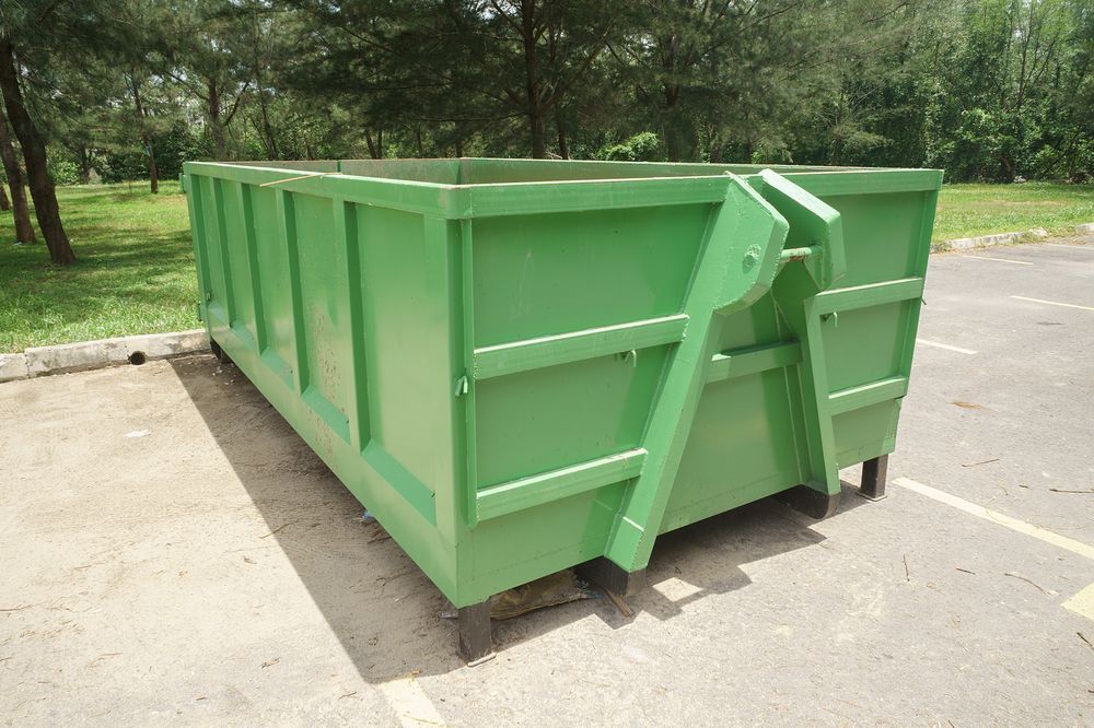Green metal dumpster on a concrete lot near trees and grass — UBIN in Broadwater, NSW