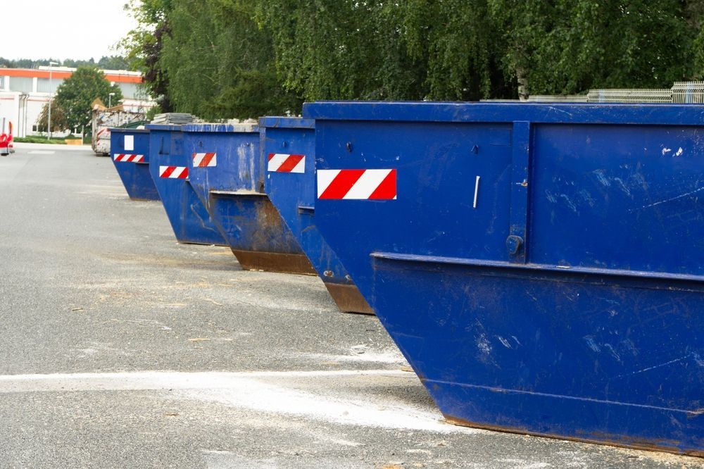 Blue construction dumpsters lined up on a paved lot outdoors — UBIN in Broadwater, NSW