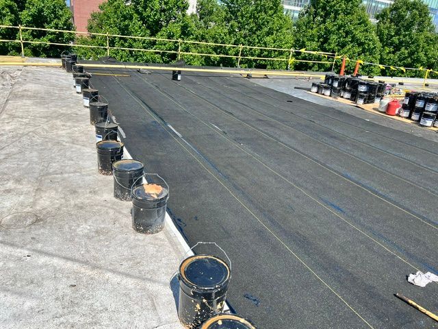 Buckets of asphalt are sitting on top of a roof.