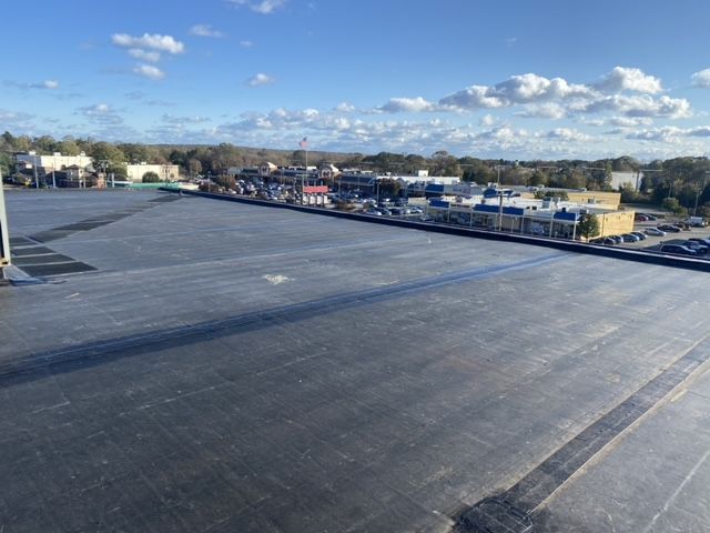 The roof of a building with a lot of cars parked in the distance.