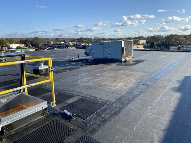 A roof with a yellow railing and a white box on it