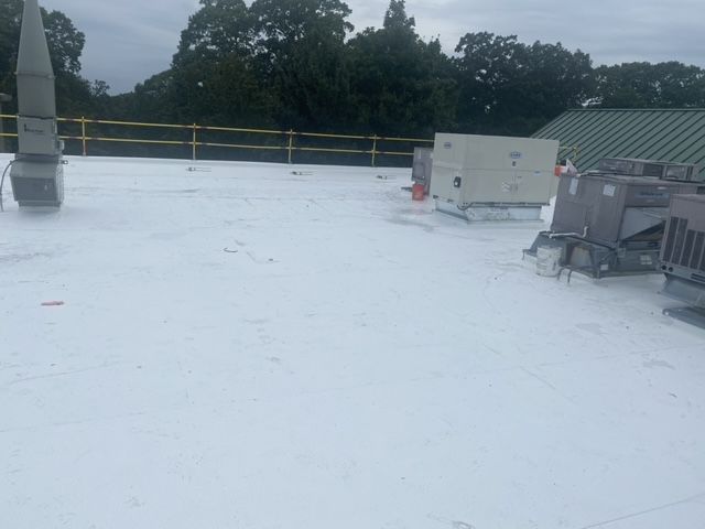 A white roof with a green roof and trees in the background.