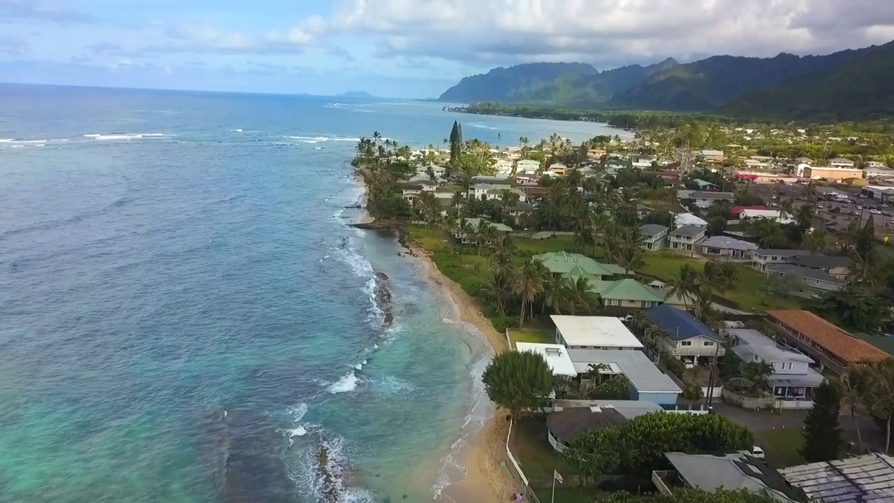 Aerial view of Oahu's North Shore coastline with surf breaks and mountains
