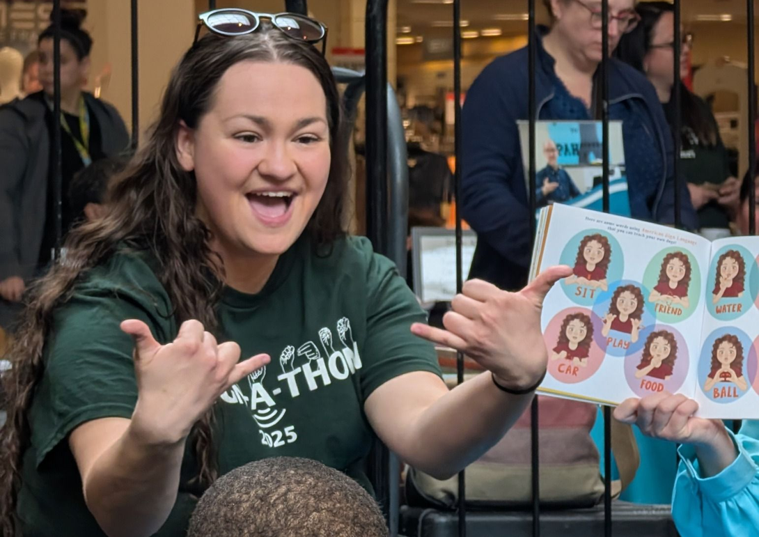 Smiling woman reaches out at a booth, receiving a sheet of illustrated face stickers