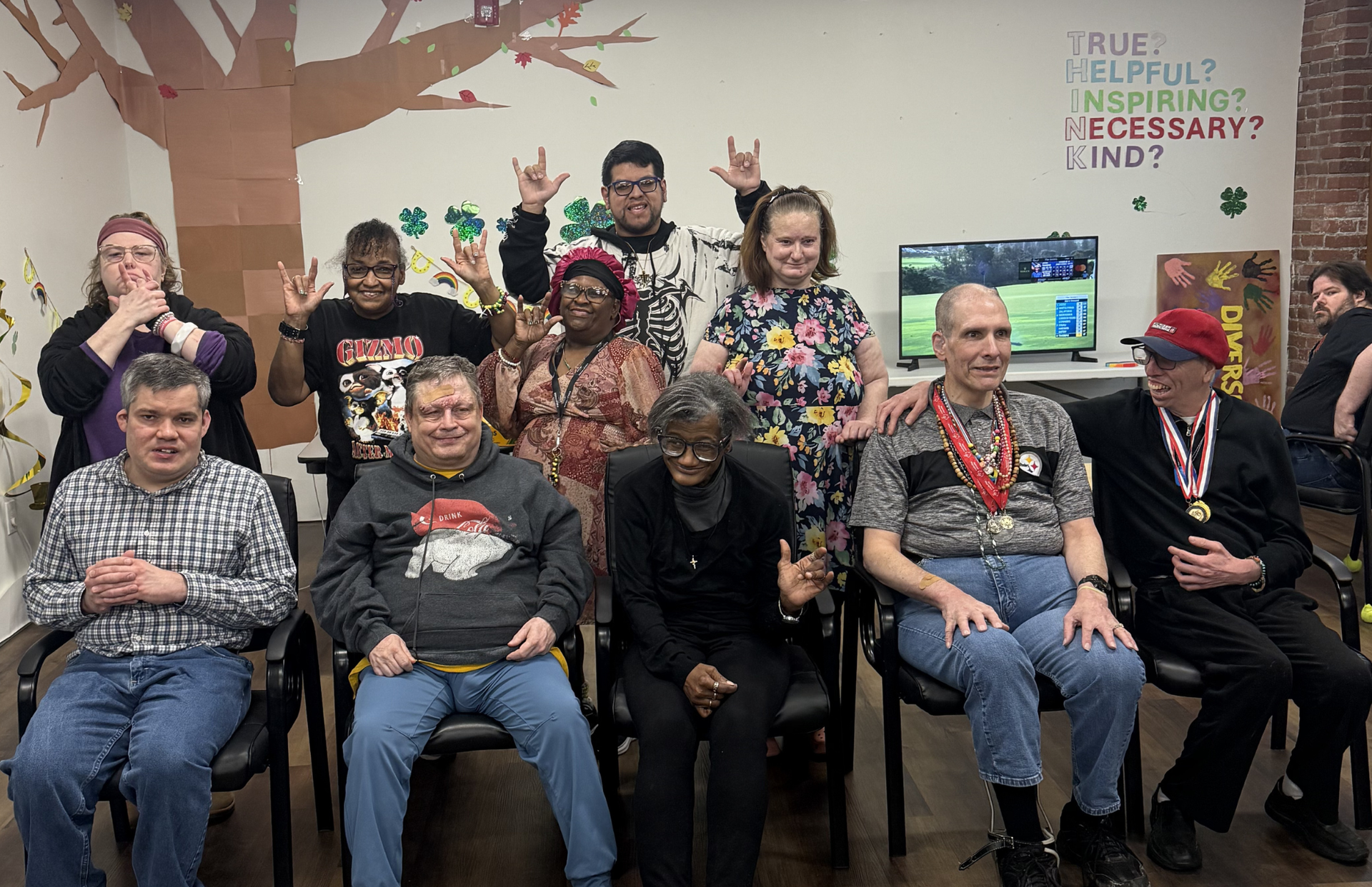 Group of adults posing indoors with painted tree backdrop and festive holiday decorations
