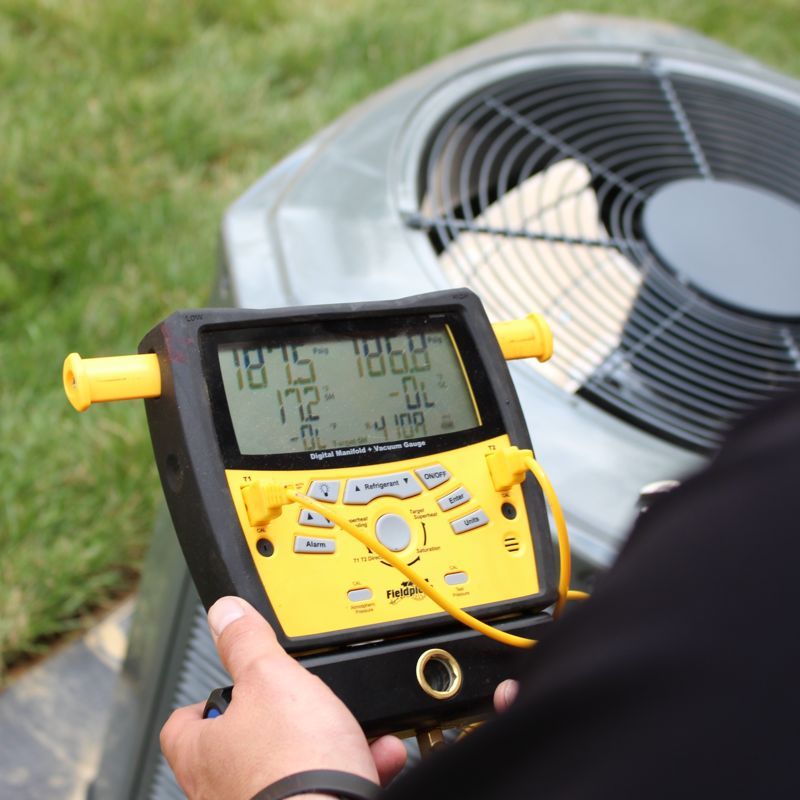 A person is measuring the temperature of an air conditioner