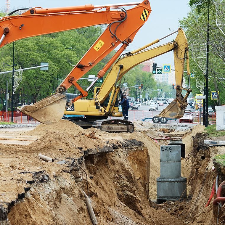 A yellow and orange excavator is digging a hole in the ground