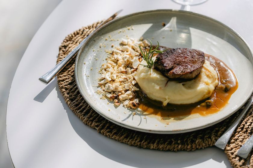 Sobremesa gourmet empratada com calda de caramelo sobre uma mesa branca, coberta com um disco de chocolate.