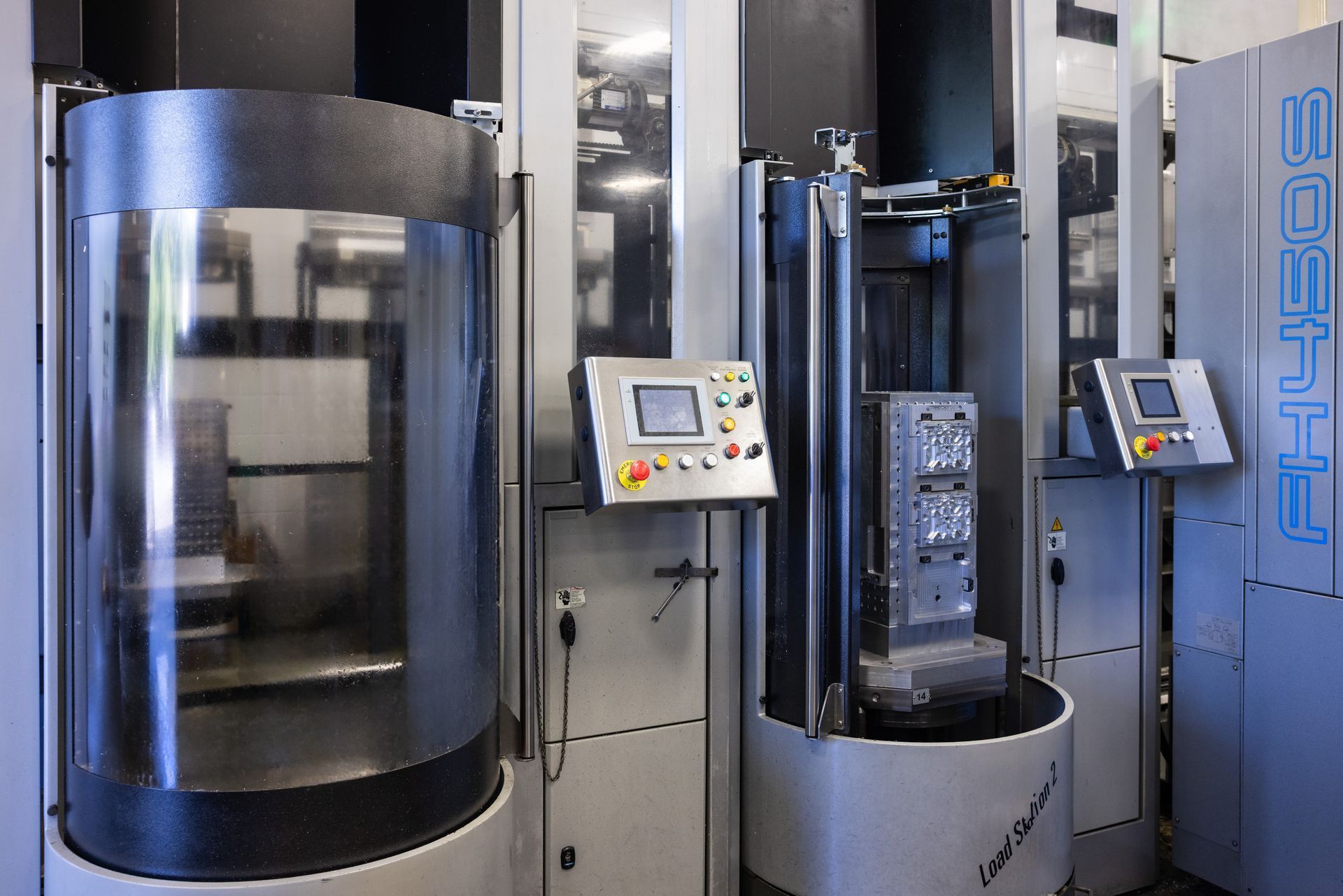 Three industrial machines with control panels. The machine on the left has a transparent cylinder. The rightmost machine says