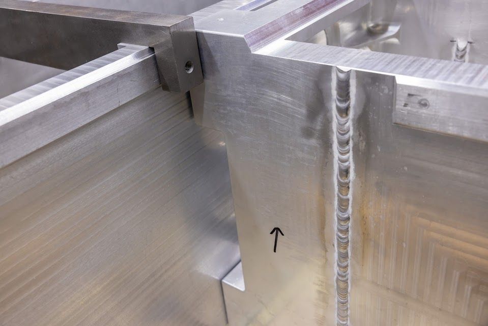 Close-up of welded aluminum frame corner with an arrow pointing to a detail.