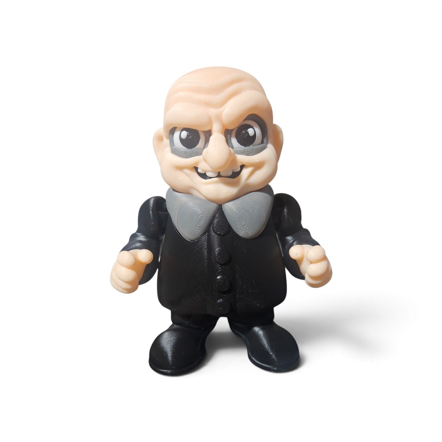 Small black-clad figurine with a bald head, gray collar, and stern expression on a white background