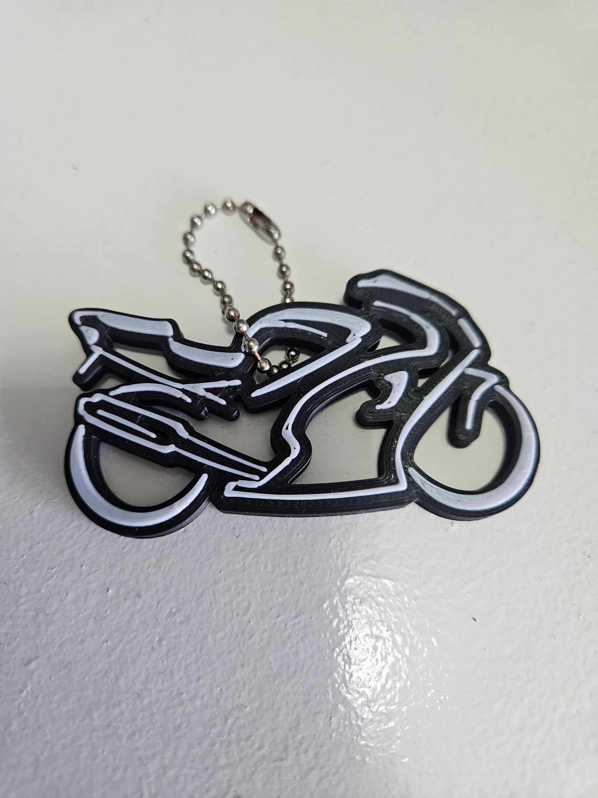 Black and white motorcycle keychain on a light surface