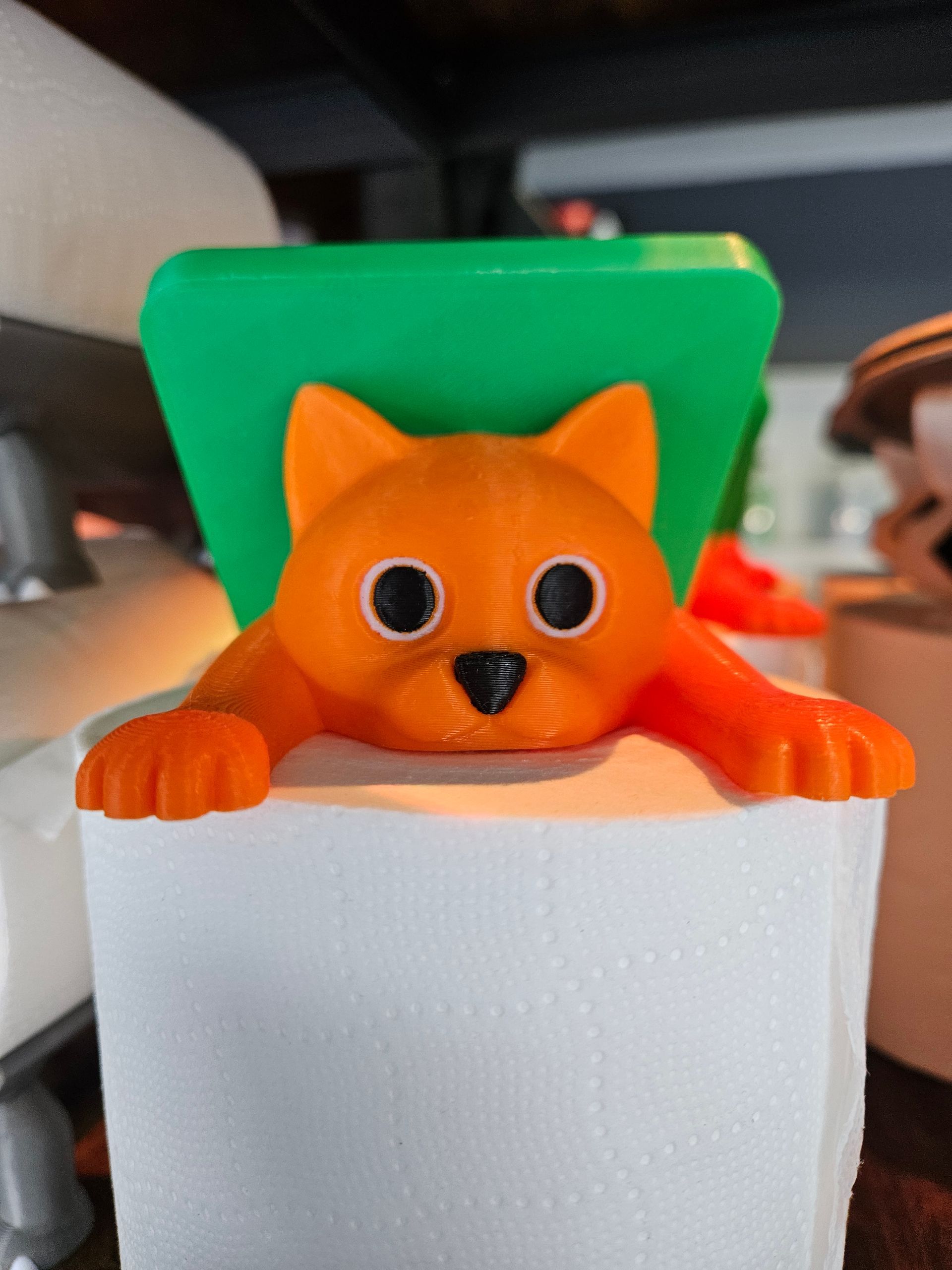 Orange fox figurine peeking over a white container with a green backrest