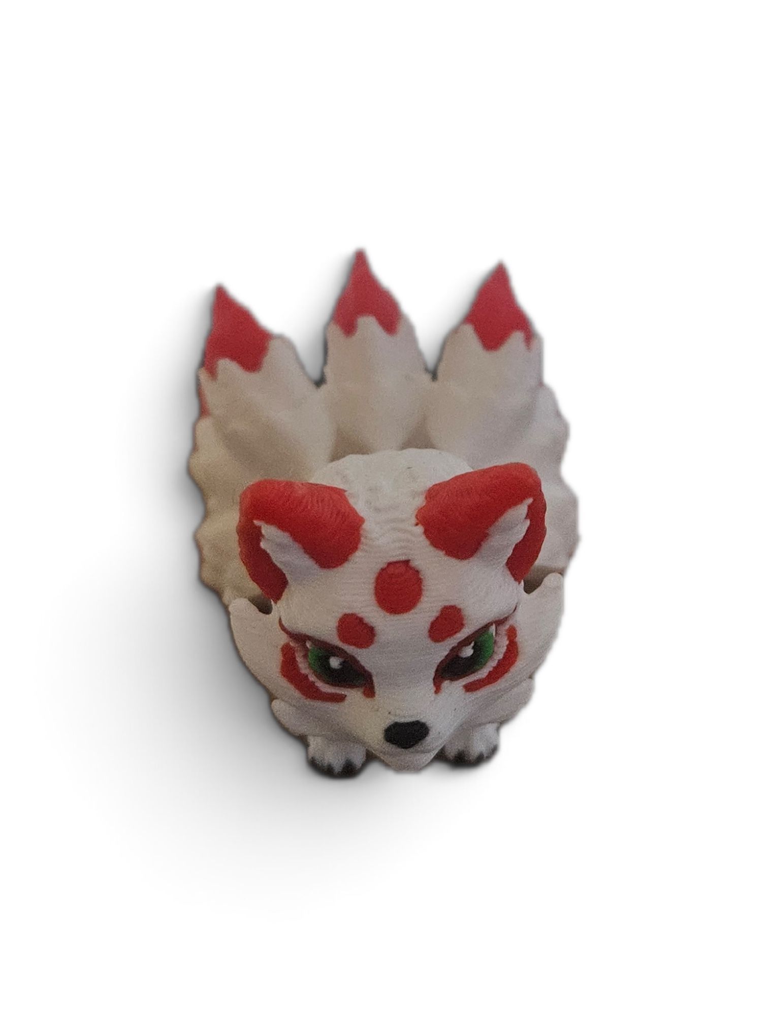 Small white fox figurine with red markings and black eyes on a plain background