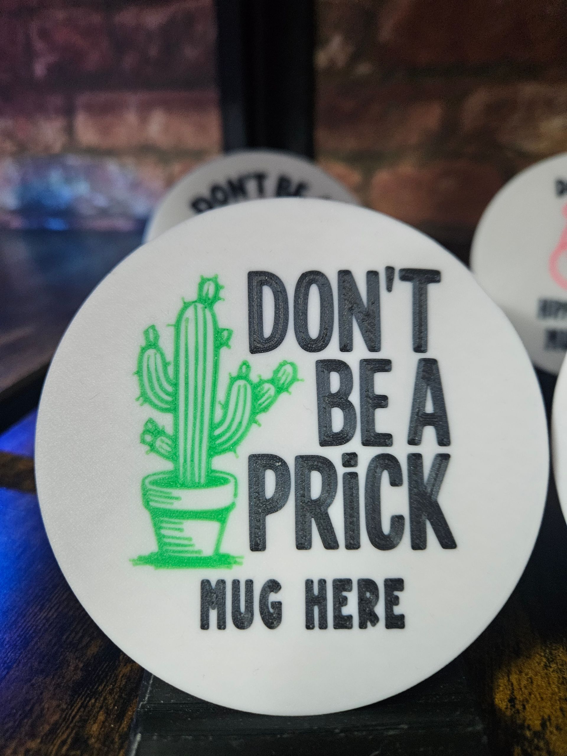 White coaster with green cactus and text:
