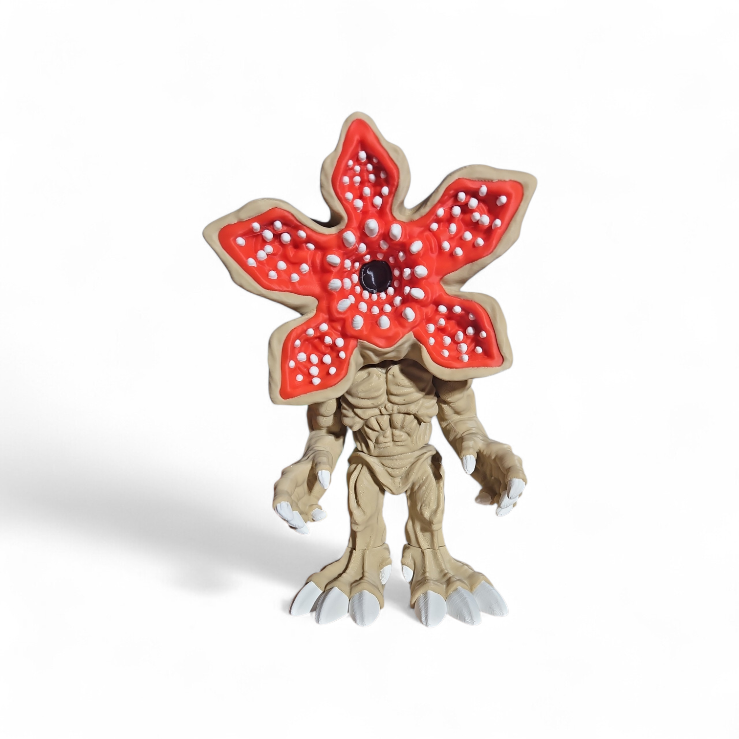 Red star-shaped flower monster figurine with beige body and white spots on a white background