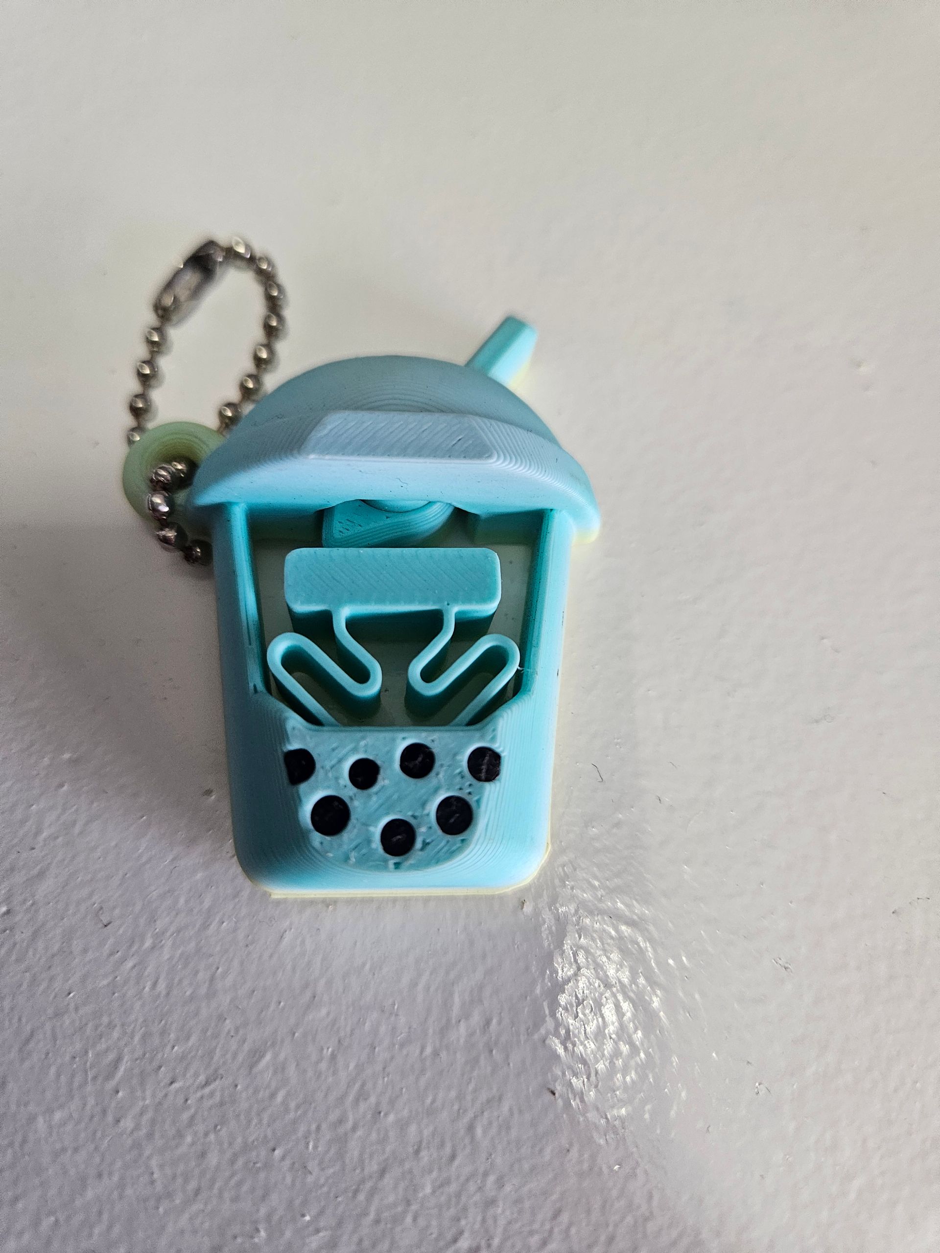 Turquoise bubble tea keychain charm with a chain and smiling face detail