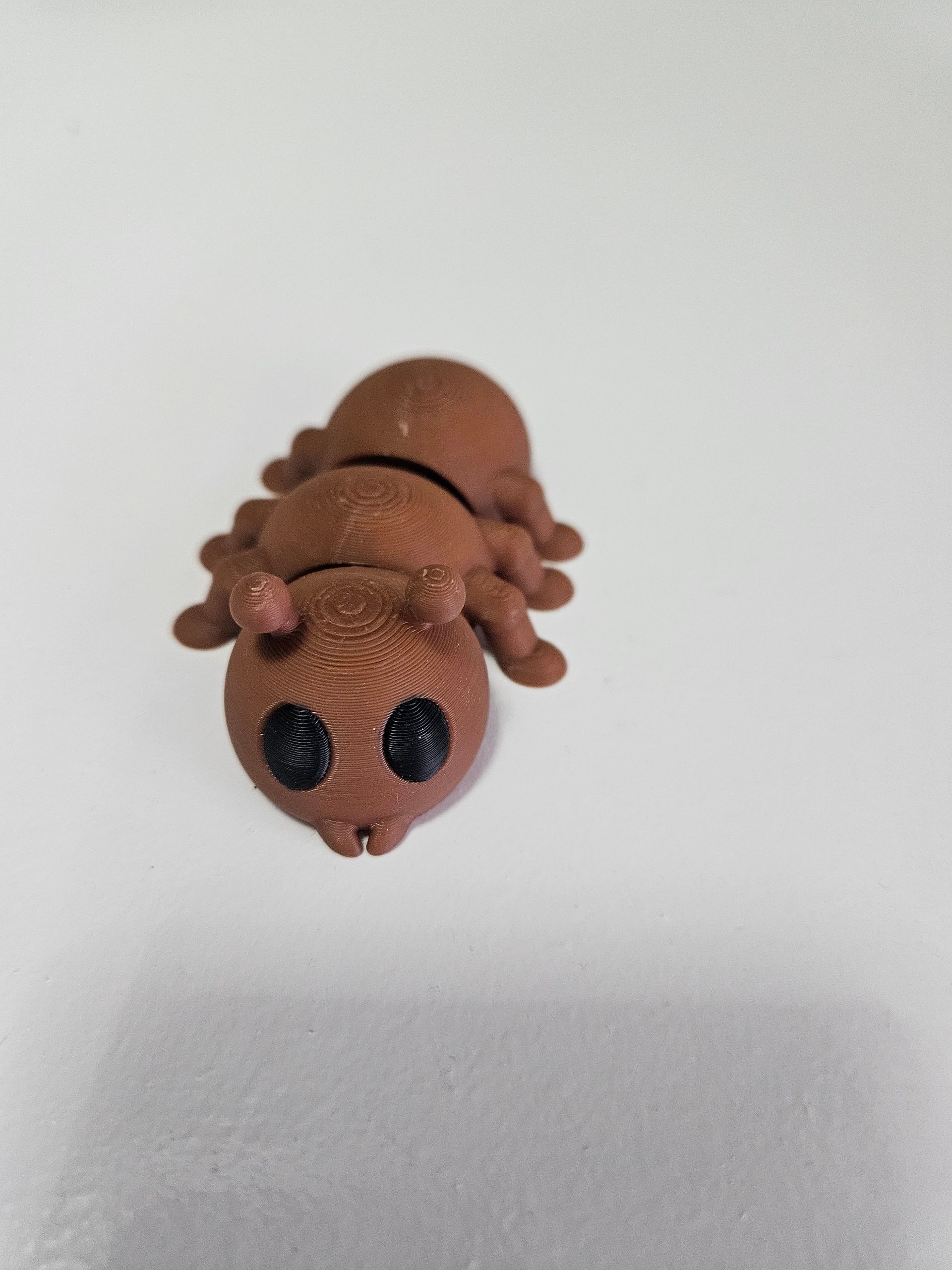 Brown fuzzy toy insect with black bead eyes on a white background