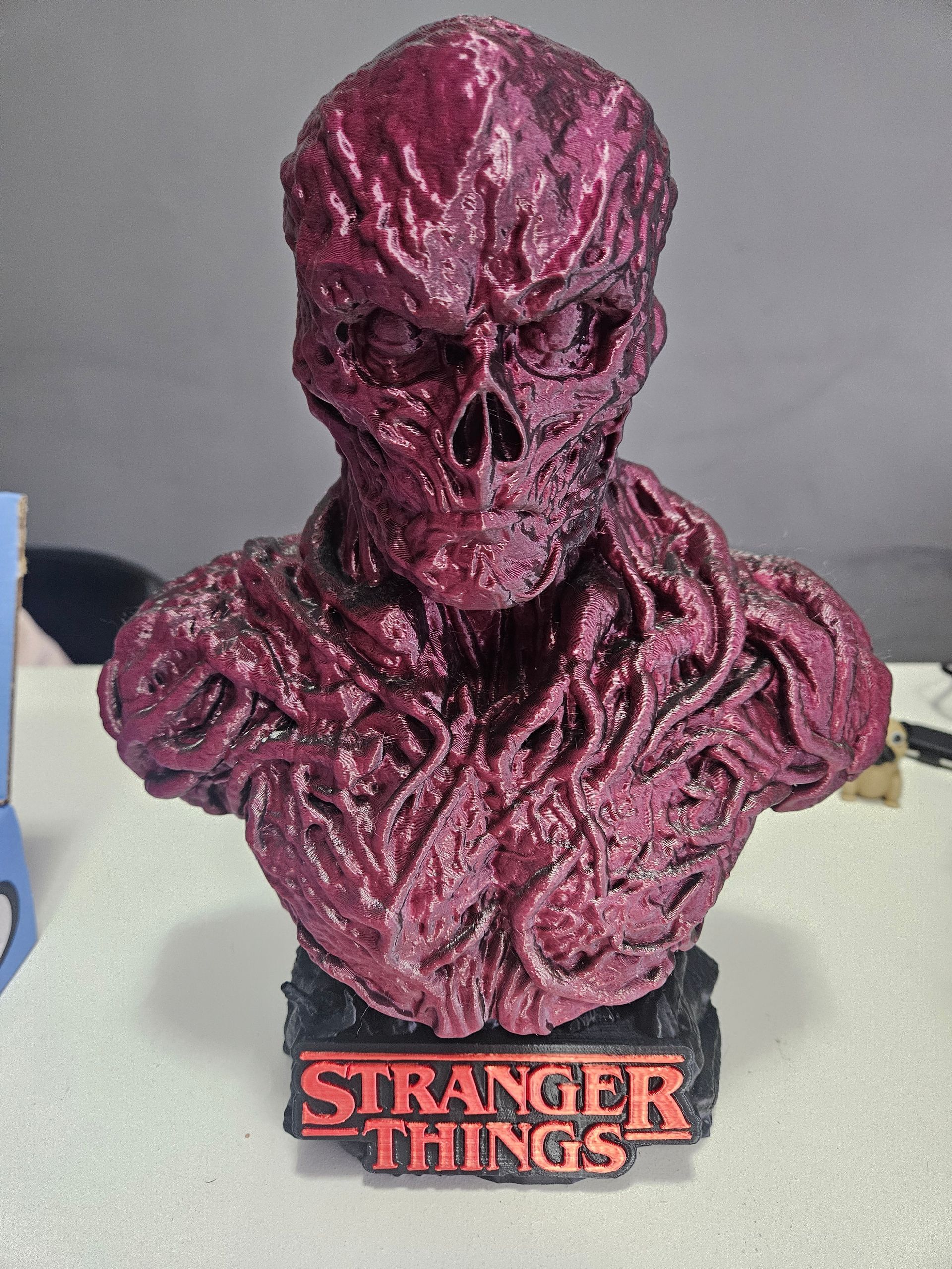 A bust of a Stranger Things creature with a crimson, textured surface; it rests on a