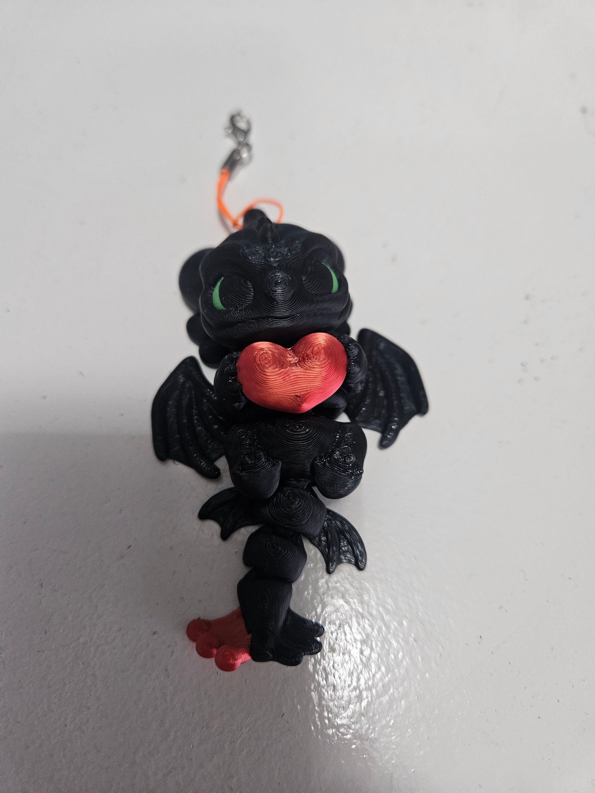 Black dragon charm with red accents and a silver clasp.